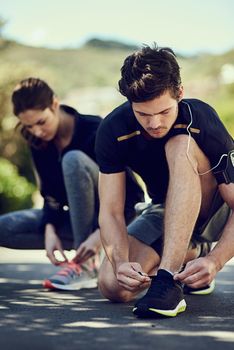 Time to lace up. two young people tying their laces before a run.