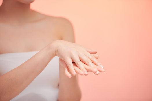 Cropped close up photo of young woman`s hands applying moisturizer cream body oil for smooth effect in spa