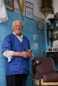 Being a barber is taking care of the people. a senior man in his barber shop.