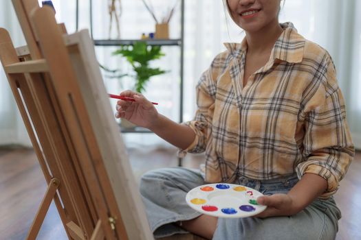 Joyful young female artist painting on canvas at workshop
