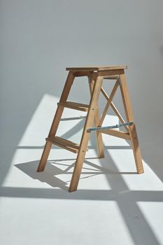 Wooden ladder in white emty room or on studio cyclorama in sunlight