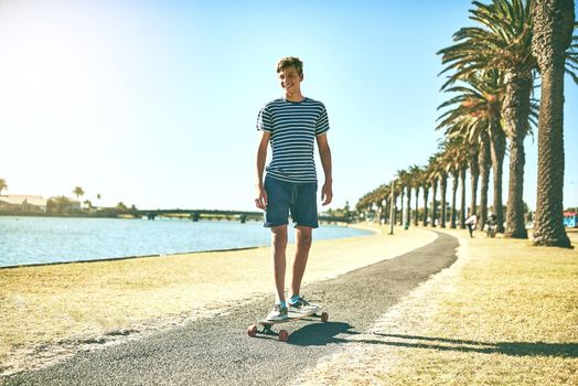 He loves being in the sun. Full length shot of a young boy skating on a pathway alongside a lagoon.