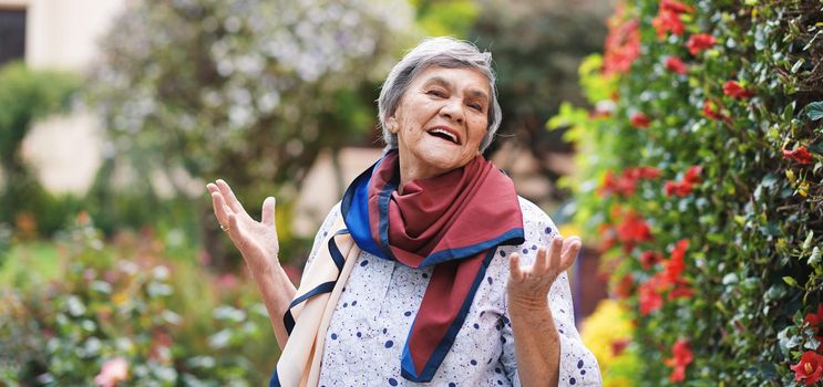 Portrait happy old woman smiling enjoying retirement wearing colorful scarf in beautiful garden