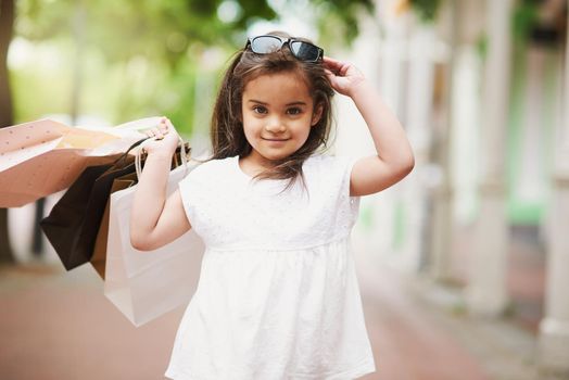 Shopping is my new hobby. Portrait of an adorable little girl holding shopping bags while out in the city.