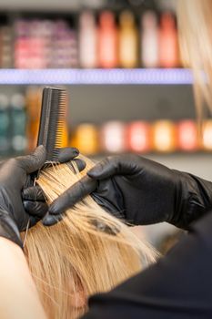 Hairdresser combing client's female hair