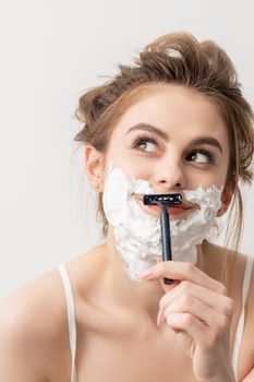 Woman shaving face with razor