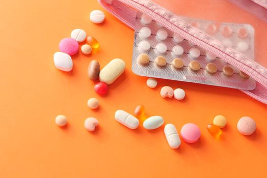 birth control pills on orange background, close up