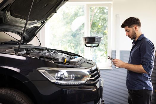 Specialist Inspecting Engine in Order to Find Broken Components. Shot for Animation of Car Service Manager Uses Tablet Computer with Futuristic Augmented Reality Diagnostics Software