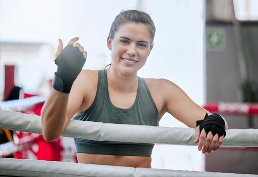 Active, fit and young female boxer ready for a boxing exercise, workout and training at a gym. Athletic, happy and sporty woman enjoying fitness and exercising at a sport and wellness studio or club