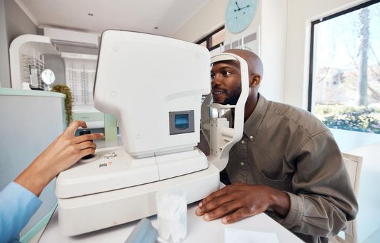 Eye test, exam or screening with a young man at the optometrist using an automated refractor. Patient testing his vision and eyesight with an optician for prescription glasses or contact lenses