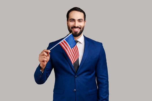 Portrait of positive optimistic bearded man holding united states of america flag, patriotism.