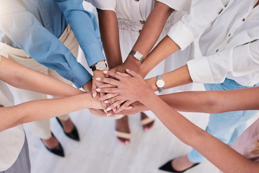 United, successful or ambitious businesspeople hands stacked together in a work office. Business professionals having fun standing with their hands piled for motivation during a meeting from above