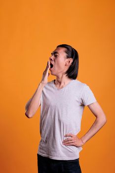 Sleepy asian man yawning, covering mouth with hand