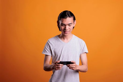 Asian teenager playing video games on phone