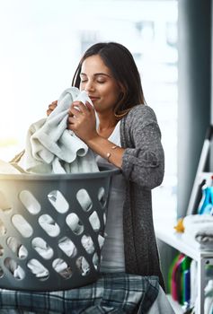 The refreshing smell of clean laundry. a young attractive woman doing her laundry at home.