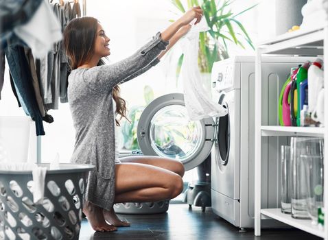 Not a single stain in sight. Full length shot of an attractive young woman doing her laundry at home.