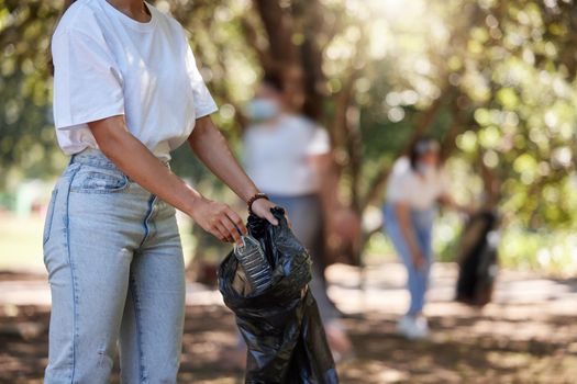 Volunteer, recycle and reduce global waste by picking up litter, dirt and garbage outdoors in a park. Closeup of young female NGO activist cleaning pollution from the environment for sustainability