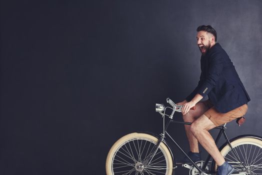 Bicycles fill him with childlike joy. a trendy young man riding a bicycle in studio.