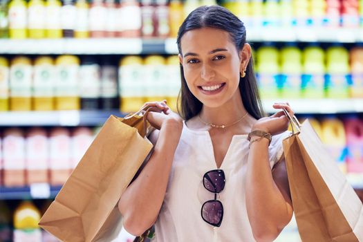 Portrait of satisfied woman shopping for groceries, smiling as she buys at the supermarket. Cheerful, young and shopaholic caucasian woman purchasing in store, buying food and products for sale.