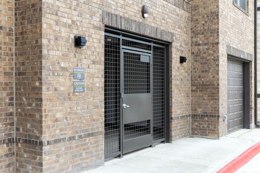 Entrance to the courtyard of a modern residential complex, lattice gates with a wicket and an entrance portal to the underground parking. Residents safety concept.