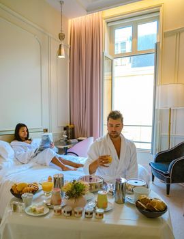 Morning wake up in bed in Paris with breakfast coffee and a newspaper,men and woman honymoon