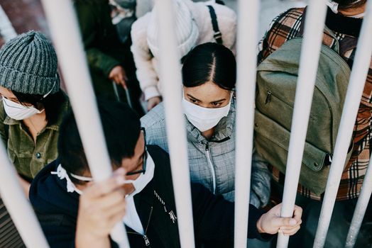 Covid travel ban, lockdown or border control to prevent spread of pandemic virus, contagious disease or illness. Travelers in masks facing quarantine, abuse and discrimination behind locked gate