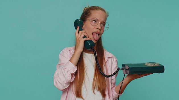 Crazy teenager girl child kid talking on wired vintage telephone of 80s, fooling making silly faces