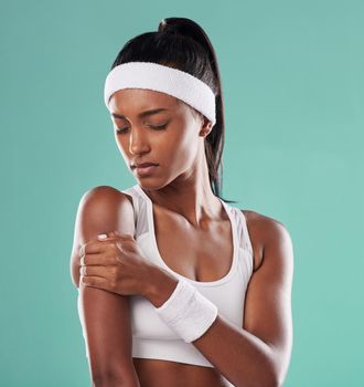 Tennis player with sports injury, hurt or pain in her arm after practice against green studio background. Professional female athlete suffering muscle strain, accident and inflammation on her body