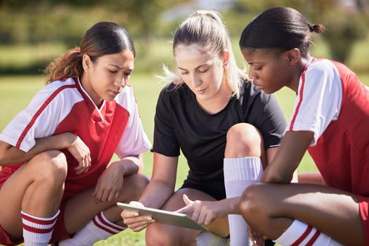 Football girls with a digital tablet checking fitness goal progress or online score on exercise app during practice on field. Sports or soccer player and coach looking at date or schedule on software