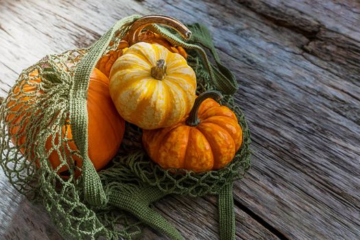 Pumpkins in alternative packaging, string bag, on a wooden background, close-up