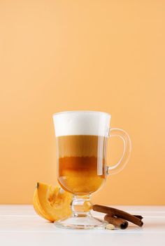 bright pumpkin spice latte in a glass mug with cinnamon
