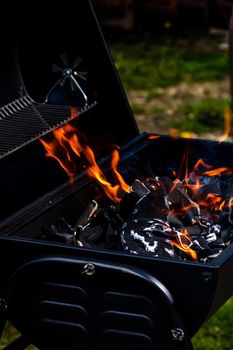 Barbecue grill pit with glowing and flaming hot open fire with red flame, hot charcoal briquettes and embers