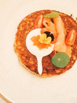 Potato fritter pancake with red caviar, salmon and sour cream in luxury restaurant outdoors in summer