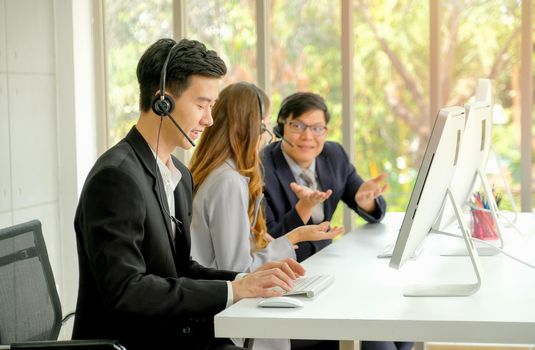 Young man work as operator with diligent habit while his co-workers talking together during working time.