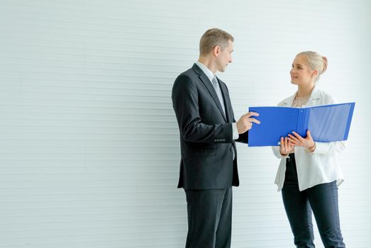 The manager man discuss with young secretary woman who hold blue file folder with white pattern background.