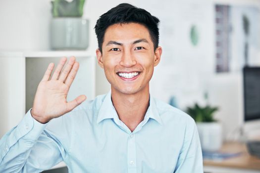 Happy business man greeting, waving and saying hello with hand gesture while smiling and looking friendly in an office. Portrait of asian entrepreneur saying thank you or welcome during testimonial