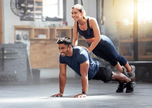 Fitness, strong and wellness couple exercising, training or workout exercise inside gym. Sporty professional woman and man or trainer doing pushup and balance in a physical endurance session