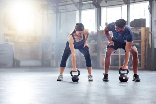 Fitness couple doing a kettlebell workout, exercise or warmup training in a gym. Fit sports people, woman and man with a strong grip, exercising using equipment to build muscles and forearm strength.