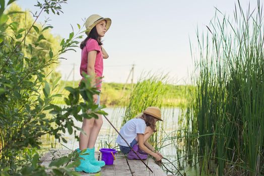 Children two girls together playing with water on lake on wooden pier in reeds
