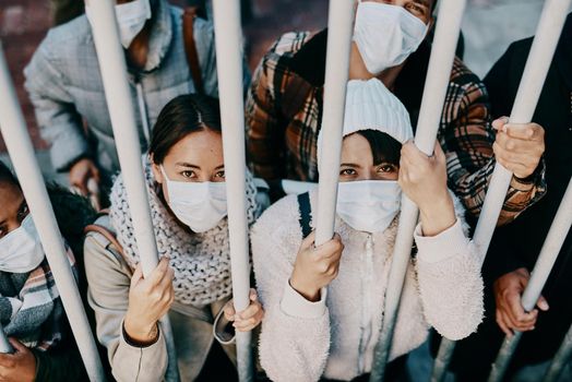 Covid travel ban, lockdown or border control to prevent spread of pandemic virus, contagious disease or illness. Portrait of prisoners in masks facing racism and discrimination behind locked gate