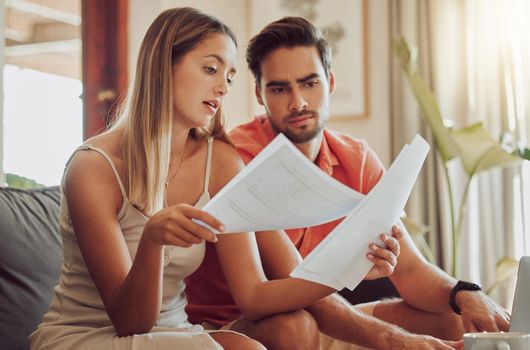 Budget, debt and mortgage with a couple reading bills and documents while checking their expenses and savings. Husband and wife looking worried while reading a loan application or contract together