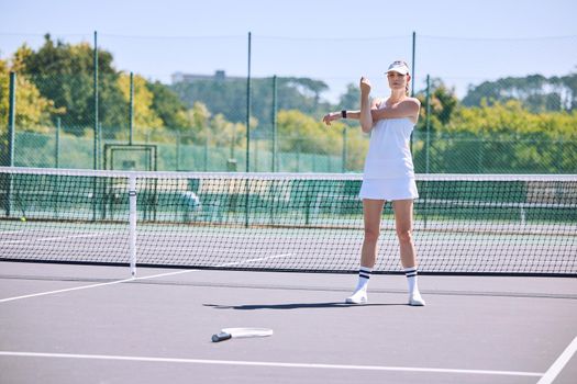 Fitness, tennis player and athlete stretching out arms before an exercise match, game or workout outside on the court. Young, active and sporty female in a sports club warming up ready for training