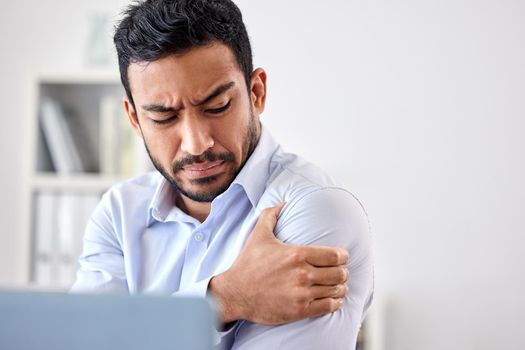 Bad muscle pain in the arm, shoulder and body after an injury and ache while working in the office. Angry, upset and frustrated businessman with a painful strain, hurt and sore sitting at his desk