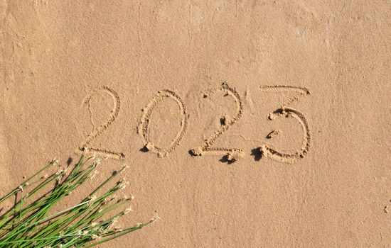 The numbers 2023 are written on the sand on the beach. The concept of the New Year. Happy New Year 2023 background. Travel during the Christmas holidays