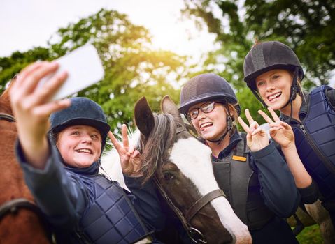Horse riding friends make the best kind of friends. a group of young friends taking a selfie while going horseback riding.