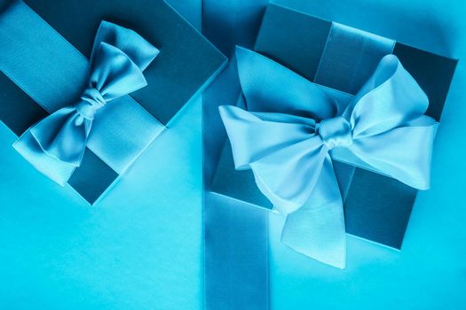 Luxury holiday gifts with silk ribbon and bow on blue background