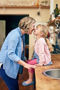 They love each other with all of their hearts. a cheerful young mother touching noses with her young little daughter in the kitchen at home.