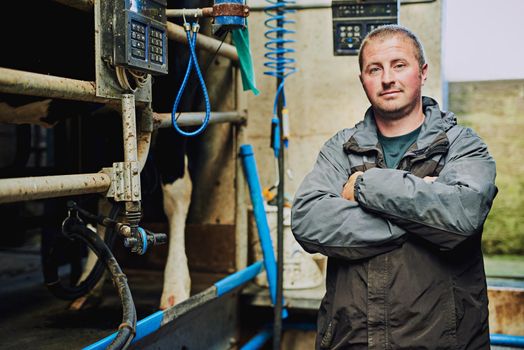 I care about my cattle. Cropped portrait of a male farmer standing with his arms folded in his dairy factory.