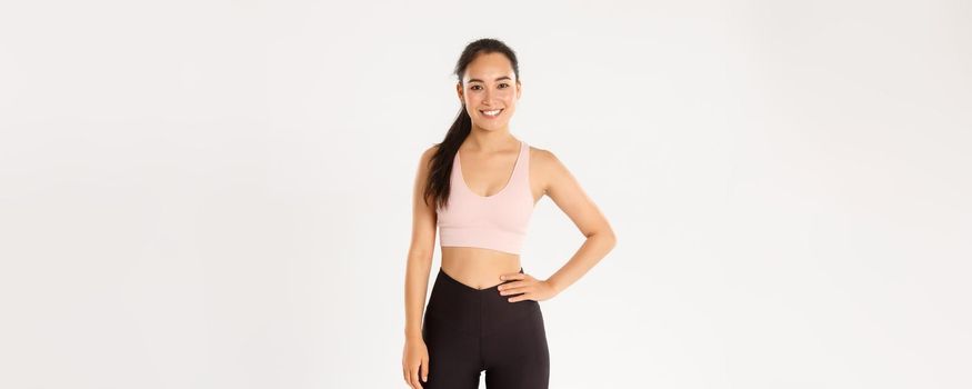 Sport, wellbeing and active lifestyle concept. Cheerful smiling asian girl promote you logo gym, special discount for membership or online classes app to workout from home, white background