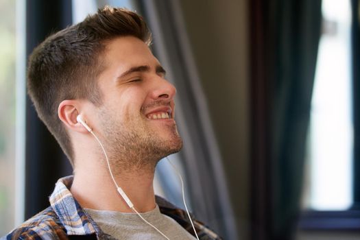 Hear the beat, feel the beat, become the beat. a young man listening to music with earphones at home.